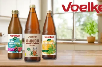 Voelkel Kombucha Flasche auf Holztisch mit Obst und Kräutern
